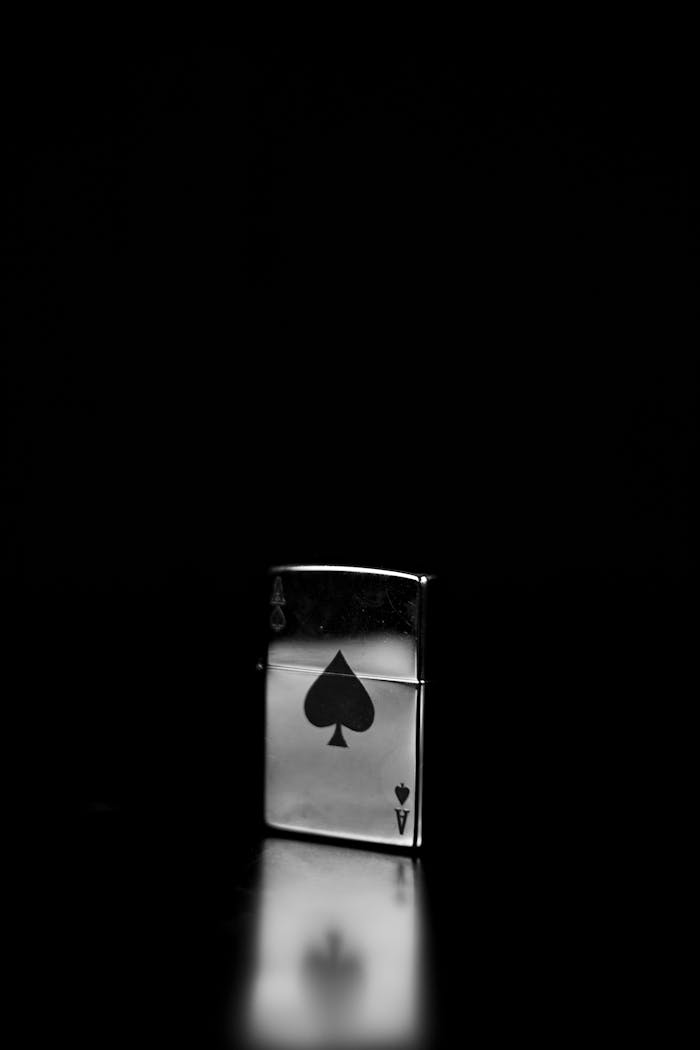 Stylish monochrome photo of a Zippo lighter featuring a spade design on a black background.