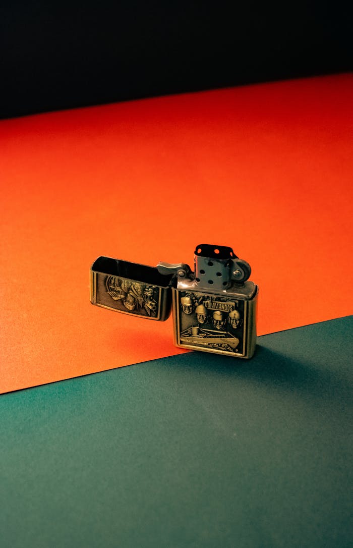 A metal lighter with intricate design placed on a colorful surface, reflecting modern style.